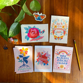 May include: A set of ten greeting cards with colorful floral and butterfly illustrations. The cards feature positive messages such as "Stay true to yourself", "Do it for your future self", "Listen to your heart", "You deserve great things", and "Imperfection is beautiful".