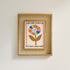 Framed artwork with a colorful flower design on a plain wall